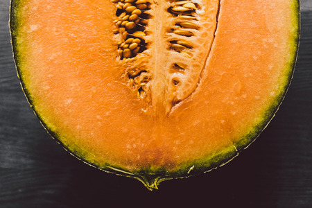 Melon texture on wooden background. Melon background. Close up view of melon cut in half on wood background. Fresh fruit. Macro view of cut melon surface.の写真素材