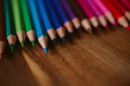 Colored pencils on wooden background with selective focus. Back to school and education concept. Crayons background for designの写真素材