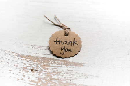 Thank you word written in a card on wooden background with selective focus. Love and gratitude...