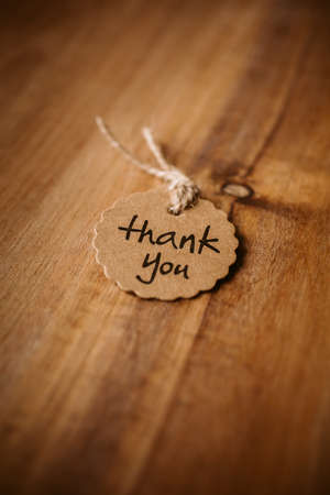 Thank you word written in a card on wooden background with selective focus. Love and gratitude concept.の写真素材