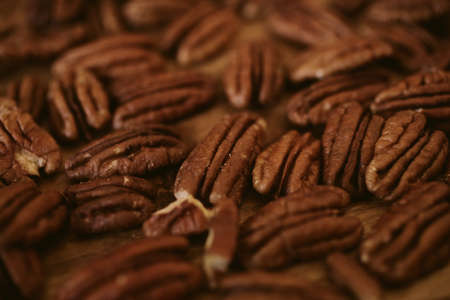 Pecan nuts close up view on wooden background with selective focus.