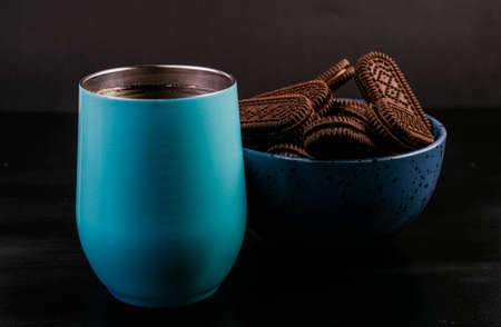 Light blue coffee mug freshly served, with a bowl of chocolate chip cookies on the side