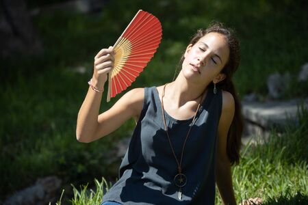 Teen cooling a heat stroke with a fanの写真素材