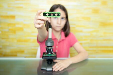 Little girl at home showing the microscope slide