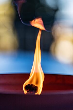 Wavering wick of a mosquito-burning candle burning in a ceramic clay pot