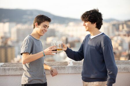 Two young men making a toast outdoorsの写真素材