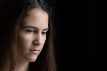 Teen girl with tears with depression symptoms in the darkの写真素材