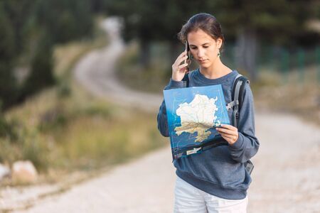 Lost traveler with map and smartphone on a forest road