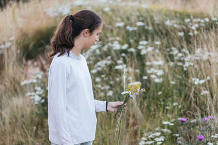 Teenage girl picking beautiful flowers outdoors