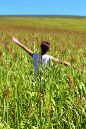 Young beautiful woman relaxing in the middle of a green cereals field during the last days of summer in the Pyrenees mountains.の写真素材