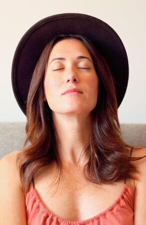 Portrait of a relaxed beautiful woman wearing a stylish hatの写真素材