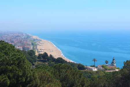 Main view of Calella de la Costa's wonderful lighhouse with the village's main beach on backgroundの写真素材