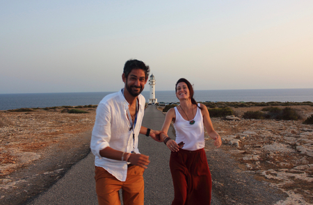 Young beautiful couple's portrait with Cap de Barberia's lighthouse on soft background, Formentera, Balearic Islands, Spain.の写真素材