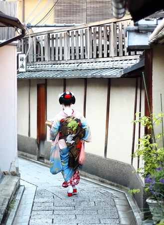A maiko walking down the streets of Gion neighborhood in the afternoon looking for a tea house in Kyoto, Japanのeditorial素材