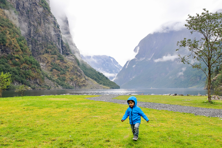 Cheerful little kid running and playing in Gudvangen village's harbour, a popular tourist destination located at the end of the NÃ¦rÃ¸yfjord in Norway.の写真素材
