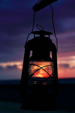 Close up of an old oil lamp with an amazing sunset landscape in background, Gili Trawangan, Lombok, Indonesia.の写真素材