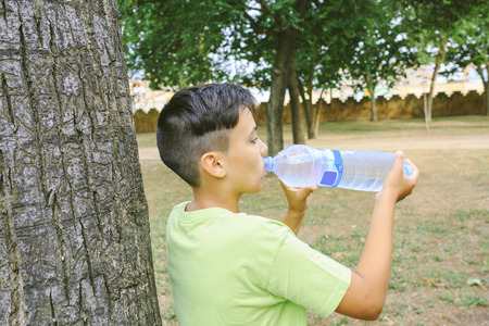 Green eyes boy  drinking water the parkの写真素材