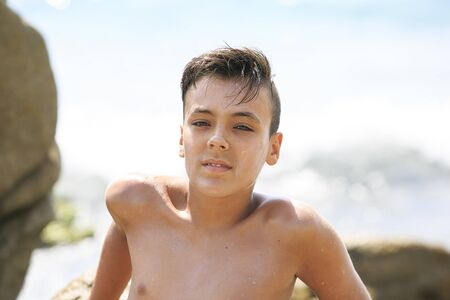 Boy with beautiful green eyes looking at the camera on the beachの写真素材