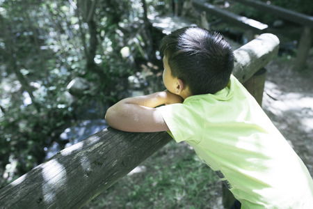 Boy looking at the river from a bridgeの写真素材