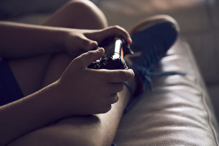 Boy playing video games in the sofaの写真素材