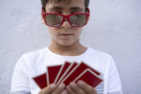 Boy with red sunglasses playing pokerの写真素材