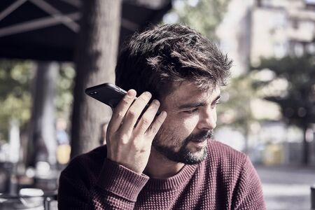 Attractive young bearded man using his smartphone in the cafeの写真素材