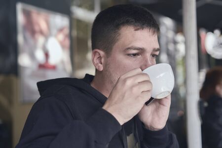 young man drinking a coffee in a cafe terraceの写真素材