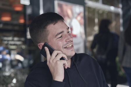 young man calling with his phone in a cafe terrace