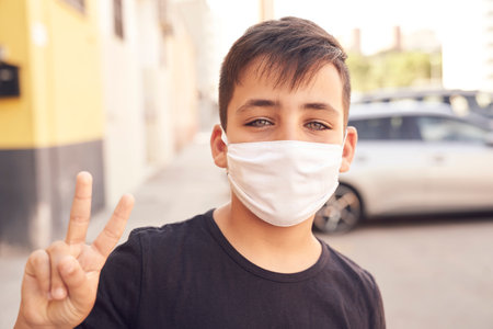 A cute little kid with green eyes wearing a mask.の写真素材