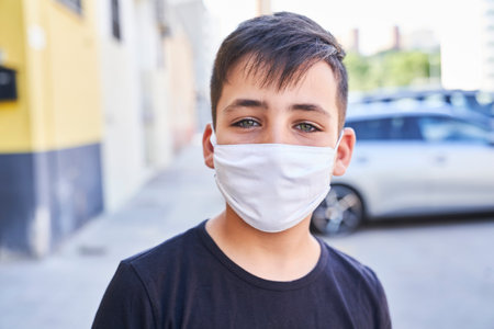 A cute little kid with green eyes wearing a mask.の写真素材
