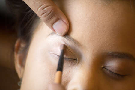 Applying eye makeup products on face.