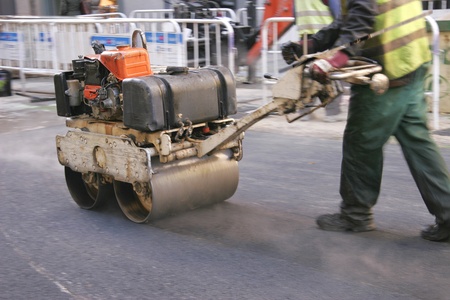 Young builder on asphalting paver machine during road street repairing worksのeditorial素材