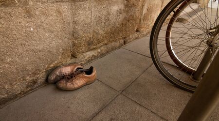 A pair of old shoes in the street near a bicyclesの写真素材