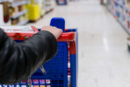 Closeup of a woman shopper with a modern shopping cart at supermarketの写真素材