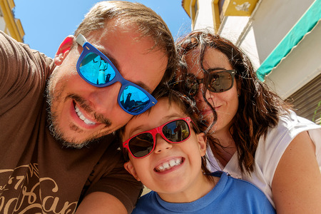 Family having fun wearing sunglasses   waving to a camera taking selfie photograph on summer holidayの写真素材