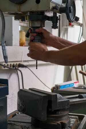 A worker with a industrial iron drill in steel factory