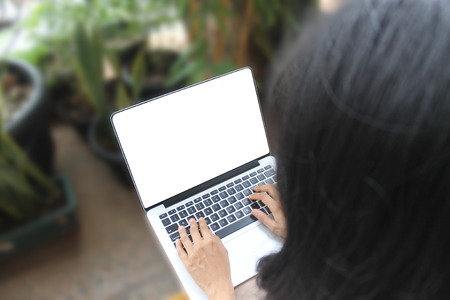 Woman outside at home garden, holding laptop with blank screen