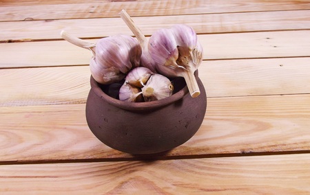 Garlic in a glay pot on a wooden background.の写真素材