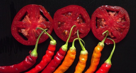 Hot pepper and tomato on a black background.の写真素材