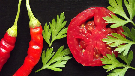 Hot pepper and tomato on a black background.の写真素材