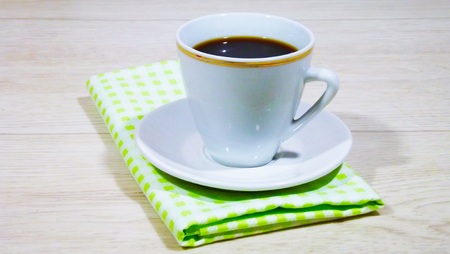 A cup of tea and a green napkin on a wooden background.の写真素材