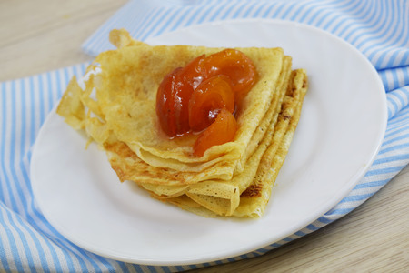 Delicious hot pancakes with apricot jam on a white plate.の写真素材