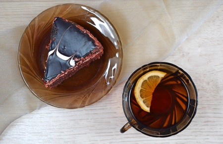 A piece of delicious chocolate cake and fragrant tea with lemon.