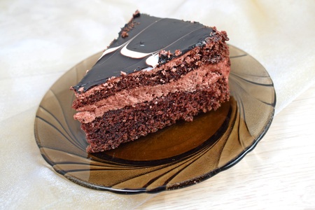 A piece of delicious chocolate cake on a brown plate and chocolates.
