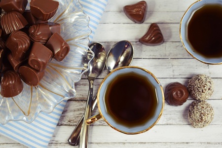 Fresh flavored tea and chocolates on wooden background.