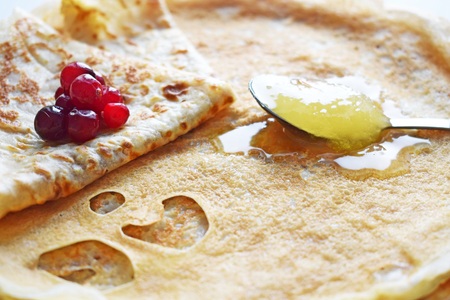 Delicious homemade pancakes with honey and fresh berries.