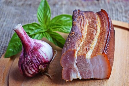 Delicious smoked bacon with spices, herbs and garlic on wooden background.の写真素材