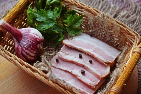 Delicious smoked bacon with spices, herbs and garlic on wooden background.の写真素材