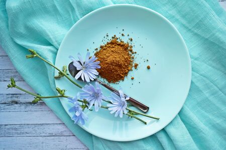 Ground chicory and blue chicory flowers on blue background. Alternative to coffee.の写真素材