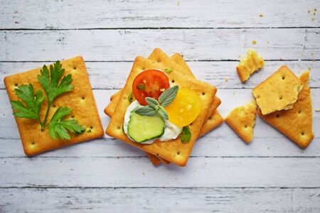 Delicious crackers with cheese sauce and vegetables.Snack on wooden background.の写真素材